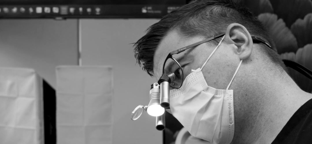 Dr. Trent Orth in loupes and mask, working chairside at Kelowna Dental Centre.