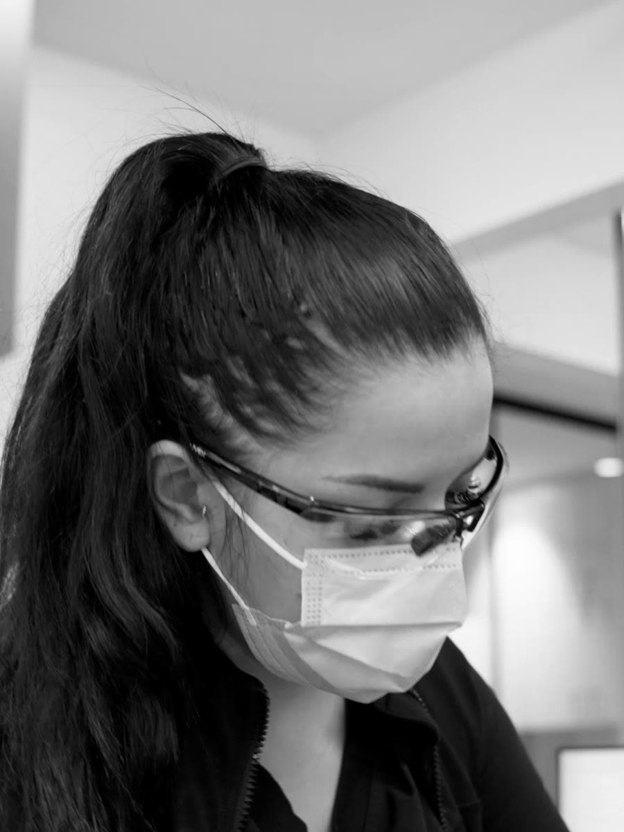 A dental assistant working chairside in loupes and a mask.